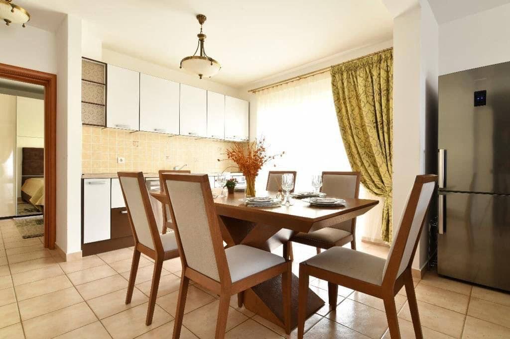 Светлая кухня-столовая с обеденным столом и современной техникой в квартире в Бечичи, Черногория.