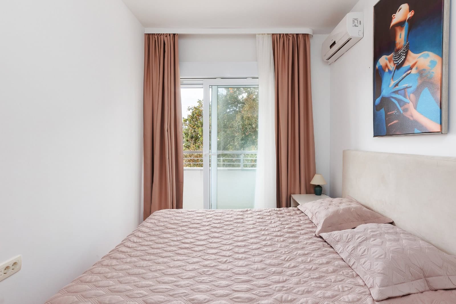 Udobna spavaća soba sa bračnim krevetom i izlazom na balkon u stanu, Bečići, Crna Gora. Moderan enterijer.
