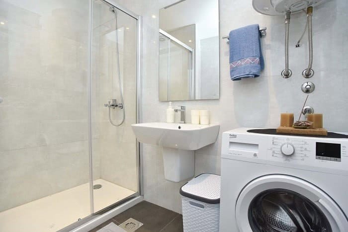 Savremeno kupatilo u stanu, Bečići, Crna Gora: tuš kabina, lavabo i veš mašina Beko.