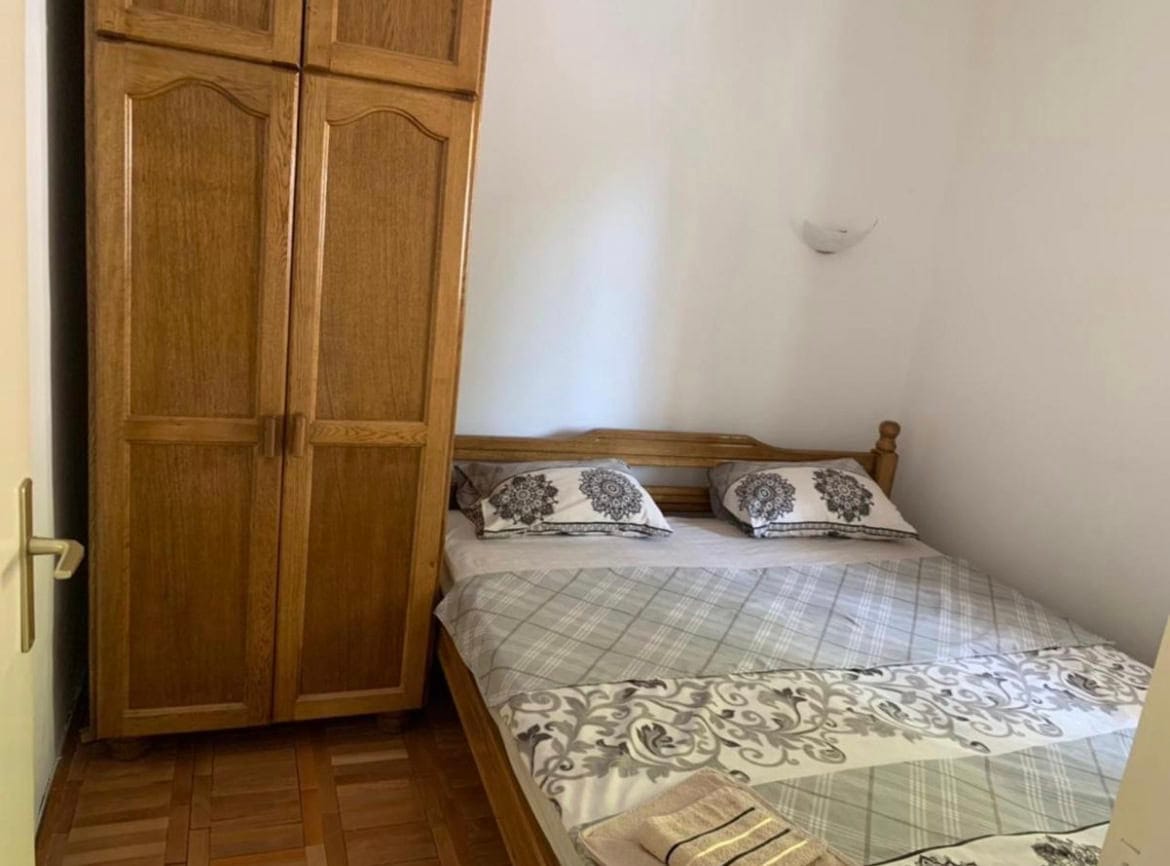 Spavaća soba u stanu na letovalištu Sveti Stefan, Crna Gora: bračni krevet i drveni ormar, parketni pod.