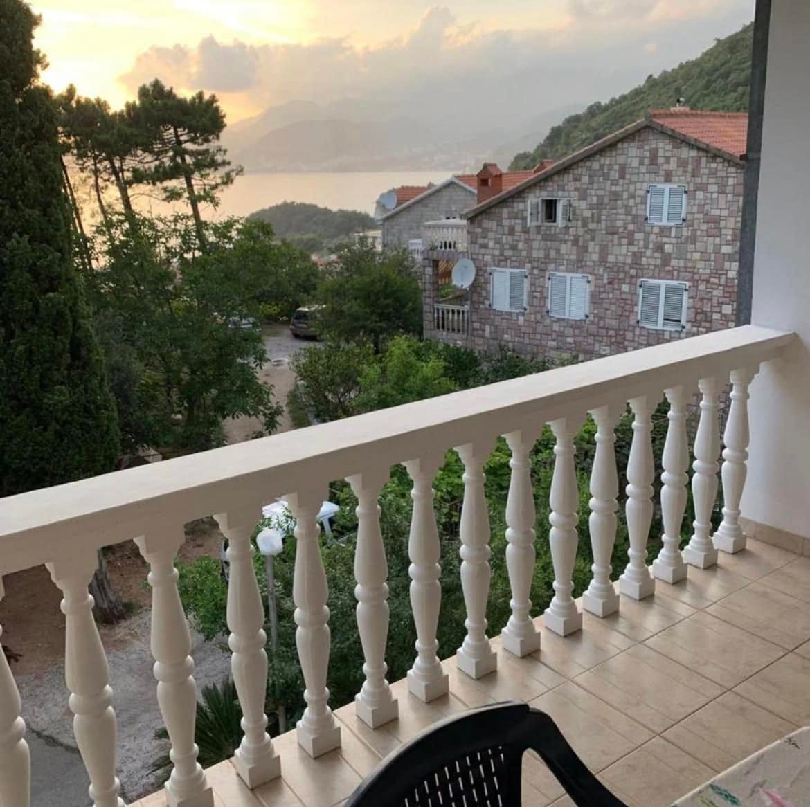 Pogled s balkona stana na Svetom Stefanu, Crna Gora: panorama mora, planina i kamenih kuća okruženih zelenilom.