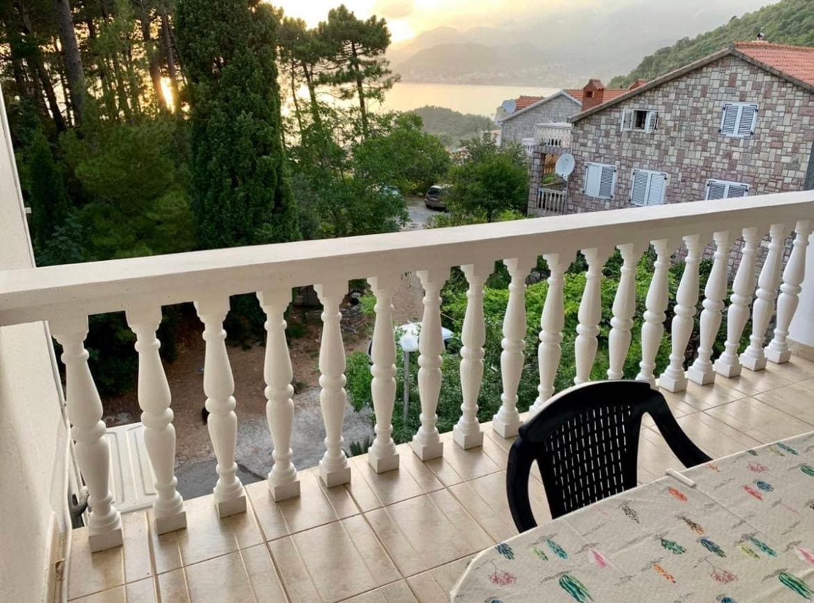 Balkon sa balustradom i pogledom na more u stanu u letovalištu Sveti Stefan, Crna Gora. Na terasi sto i stolice.