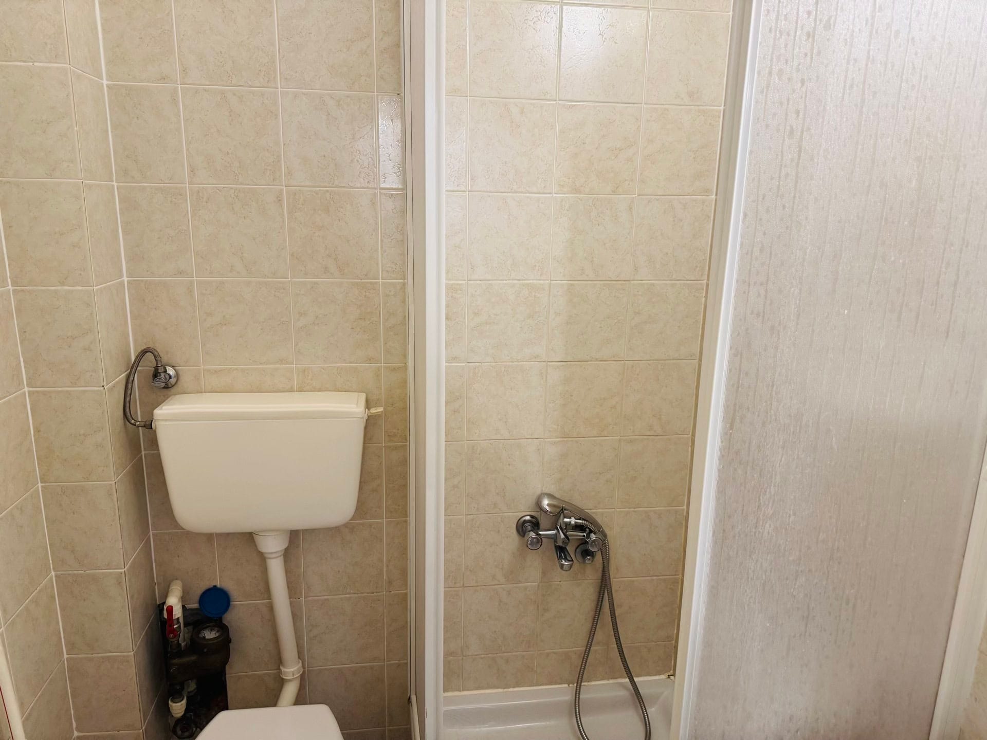 Kupatilo u stanu na Svetom Stefanu, Crna Gora: svetle pločice, tuš kabina i sanitarije.
