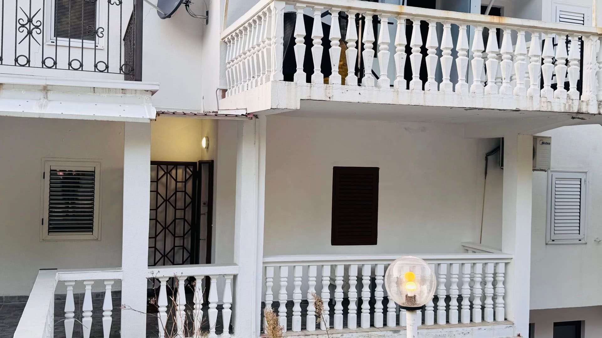 Fasada kuće sa belim balustradama i terasama u Svetom Stefanu, Crna Gora: pogled na eksterijer stana.
