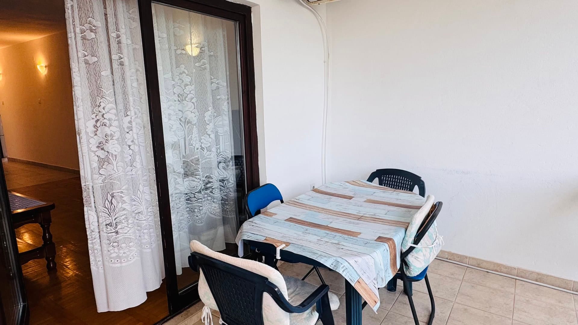 Ugodan balkon sa trpezarijskim delom u stanu na letovalištu Sveti Stefan, Crna Gora: plastični nameštaj i pločice.