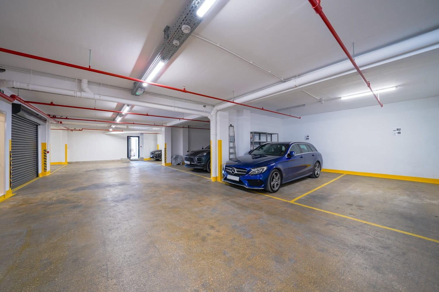 Natkrivena podzemna garaža u stambenom kompleksu u Tivtu, Crna Gora, sa obeleženim parking mestima i osvetljenjem.
