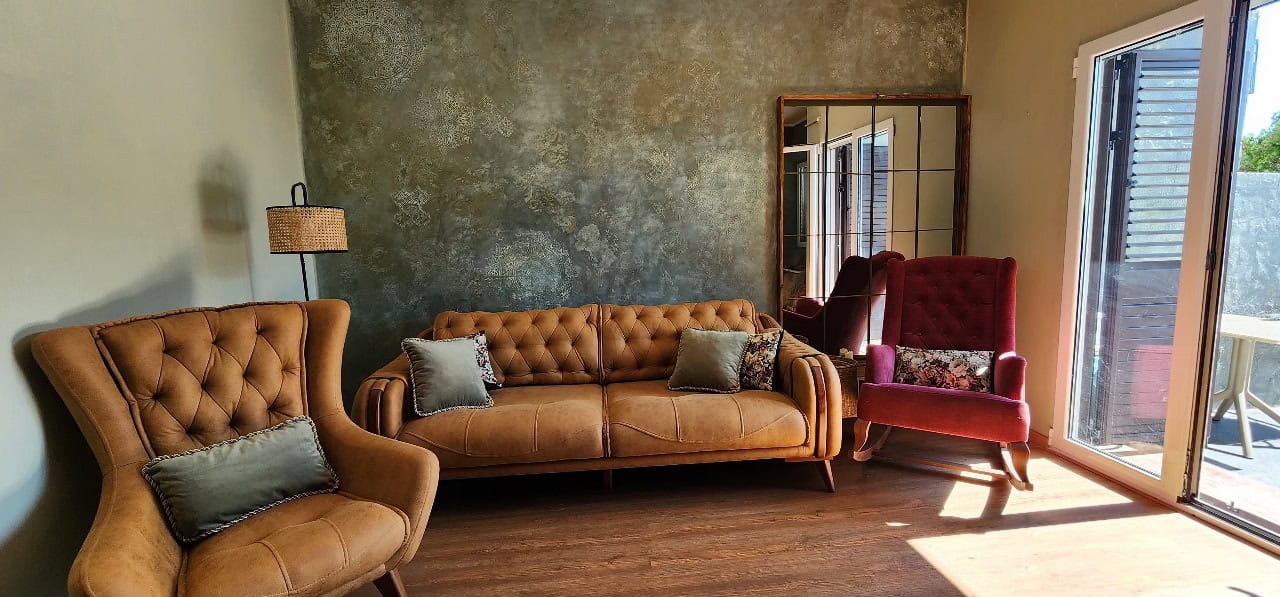 Living room in a townhouse in Petrovac, Montenegro: designer wall, soft seating, rocking chair, and access to the terrace.