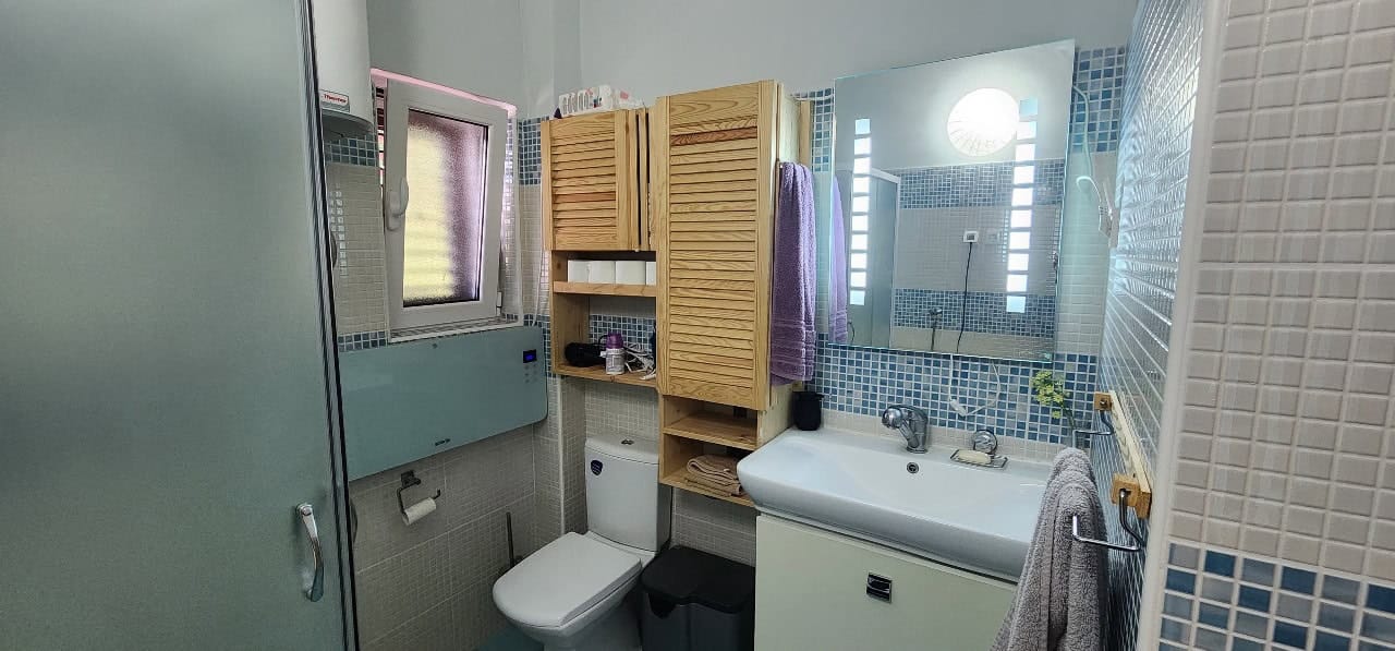 Bathroom in a townhouse in Petrovac, Montenegro: shower cabin, wooden furniture, and blue-toned tiles.