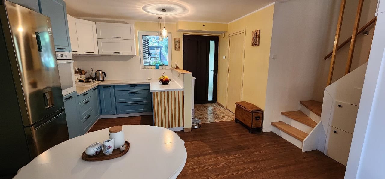 Modern kitchen in a townhouse, Petrovac, Montenegro: blue cabinetry, dining table, and staircase to the second floor.