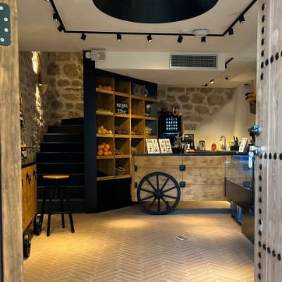 Enterijer kafića u loft stilu sa kamenim zidovima i drvenim šankom u kući u Kotoru, Crna Gora