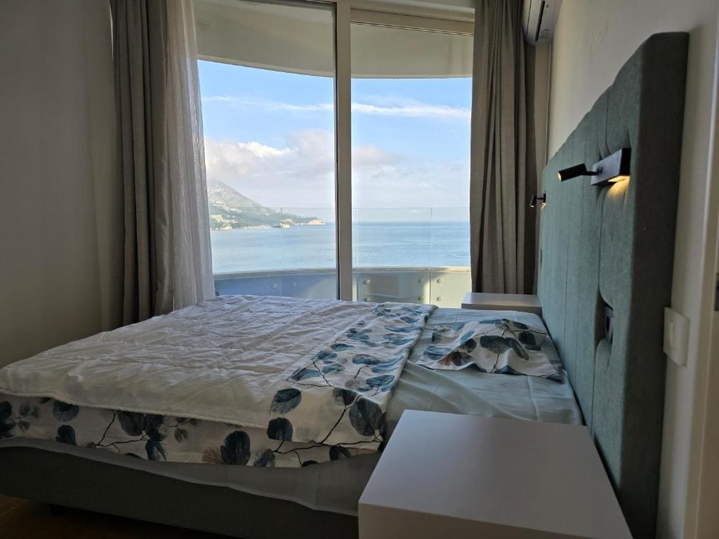 Spavaća soba sa bračnim krevetom i panoramskim pogledom na more u stanu, Bečići, Crna Gora.