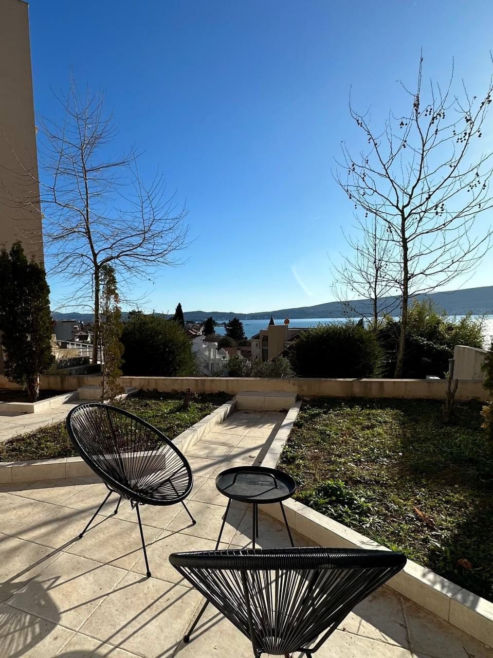 Taras z meblami ogrodowymi i panoramicznym widokiem na morze i góry w apartamencie, Tivat, Czarnogóra.
