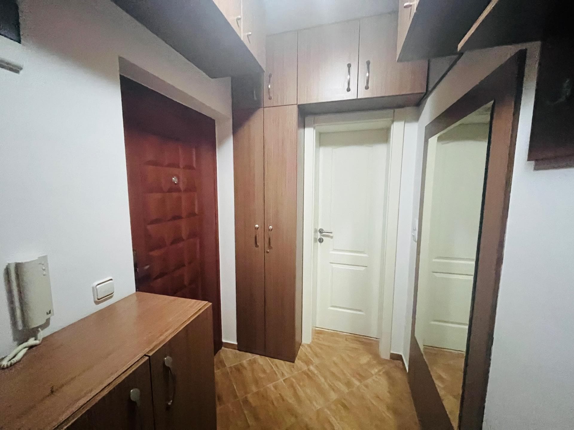 Прихожая в квартире в Сутоморе, Черногория: встроенный шкаф, зеркало и межкомнатные двери в светлом интерьере.