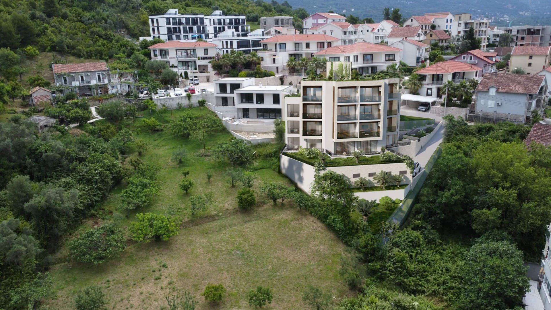 Savremeni stambeni kompleks u Tivtu, Crna Gora: pogled na zgradu sa terasama, panoramskim prozorima i zelenom površinom.