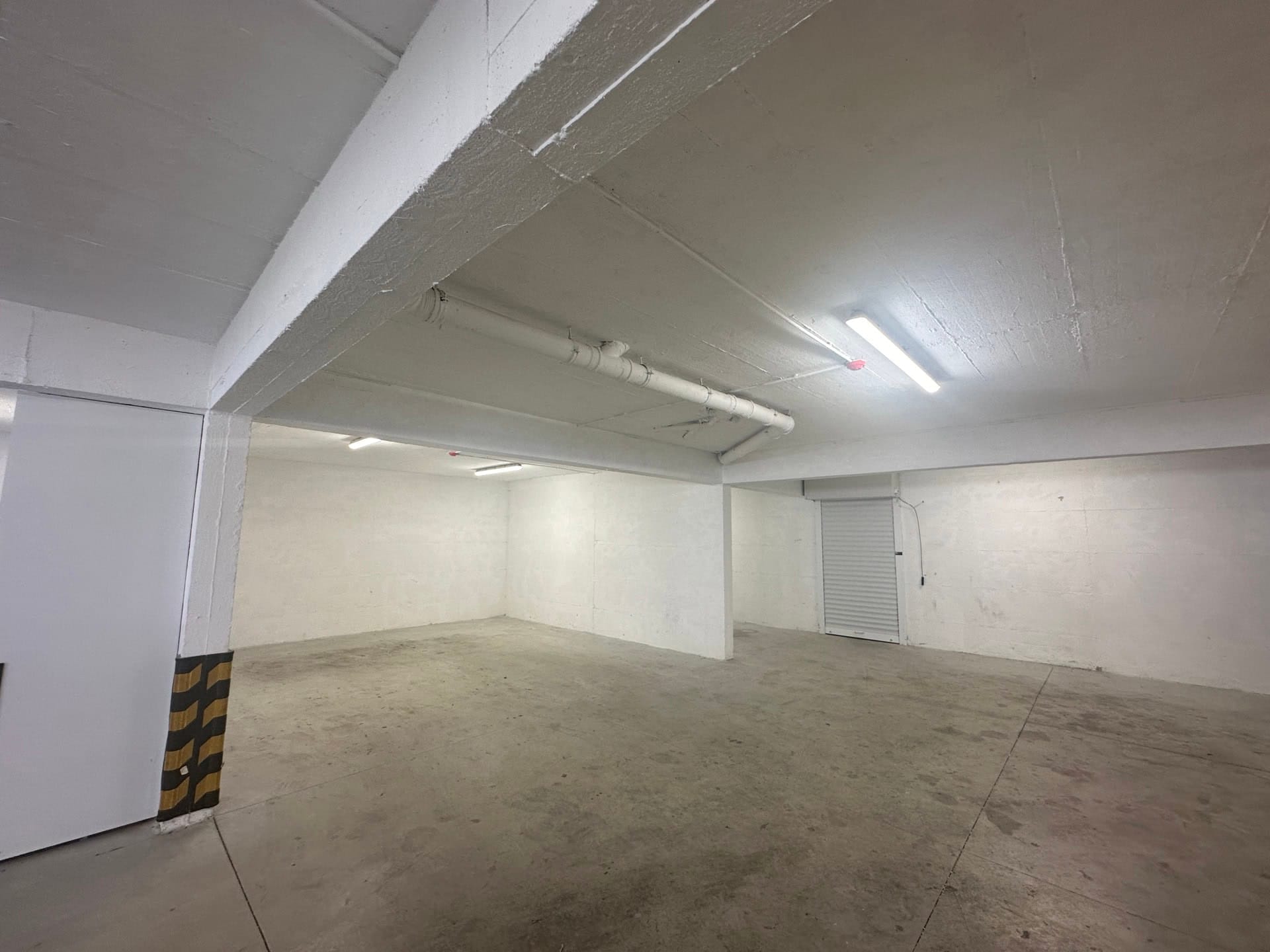 Prostrano podzemno parking mesto u stambenom kompleksu, Krašići, Crna Gora: betonski pod, osvetljenje, roletne.
