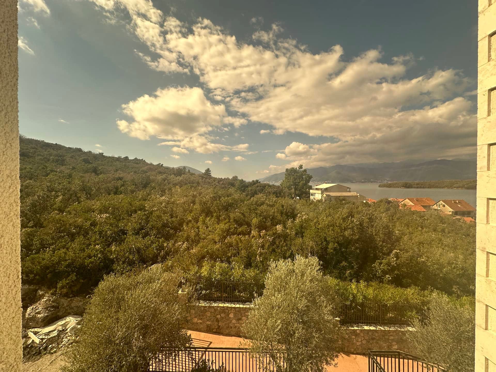 Panoramski pogled sa balkona stana u Krašićima, Crna Gora: zeleni brežuljci, masline i morski zaliv.