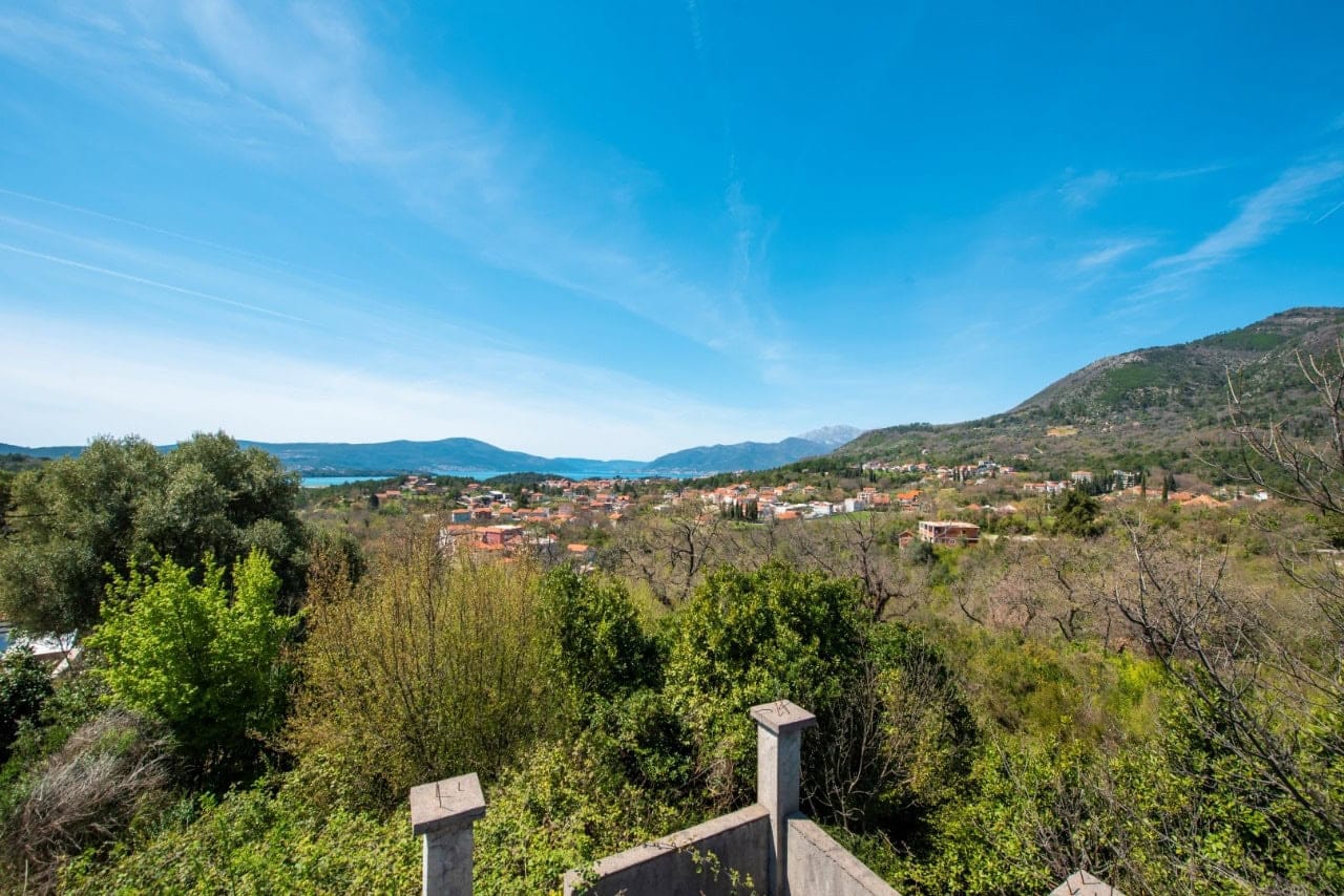 Panoramic view of the mountains and sea from a plot of land in Kavac, Montenegro: green landscape and village development.