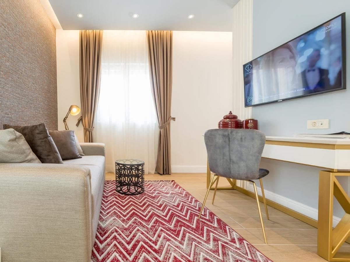 Udoban dnevni boravak u hotelu u Budvi, Crna Gora: savremeni nameštaj, TV, tepih sa cik-cak uzorkom i stilizovan dekor.