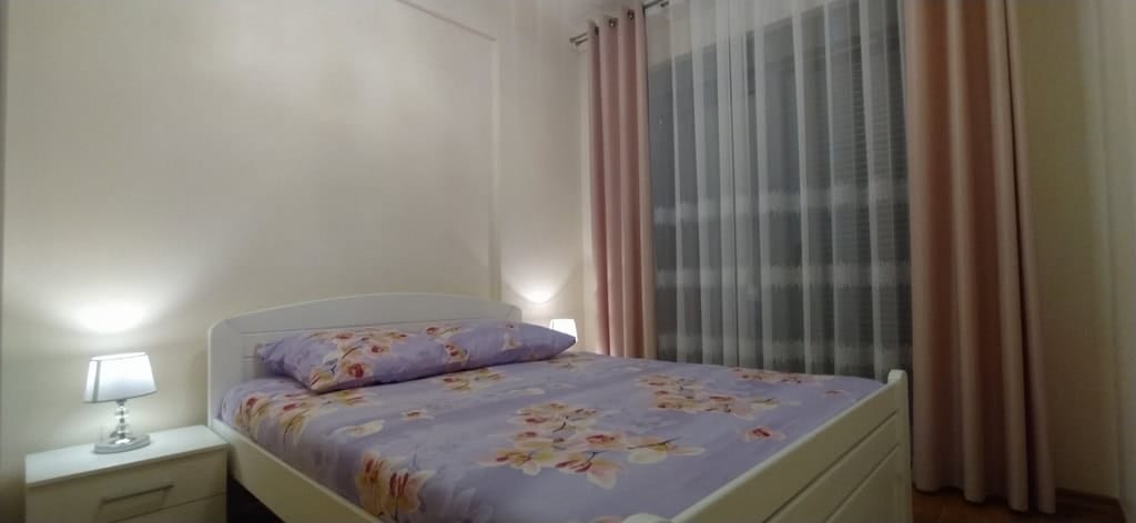 Udobna spavaća soba sa bračnim krevetom i noćnim ormarićem u stanu na prodaju, Bečići, Crna Gora.