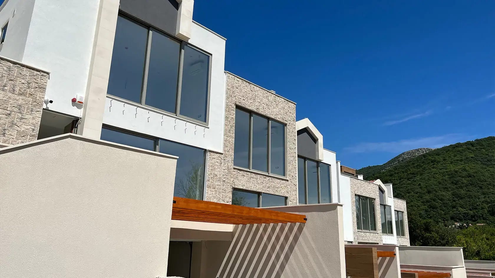 Savremeni townhouse objekti sa panoramskim prozorima i kamenom oblogom fasade u Tivtu, Crna Gora.