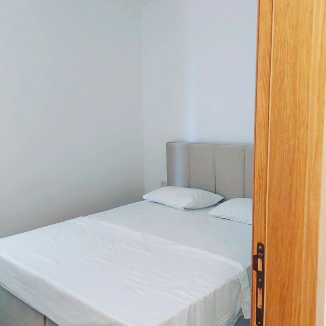 Svetla spavaća soba sa bračnim krevetom u stanu u Bečićima, Crna Gora, moderan enterijer sa belim zidovima.