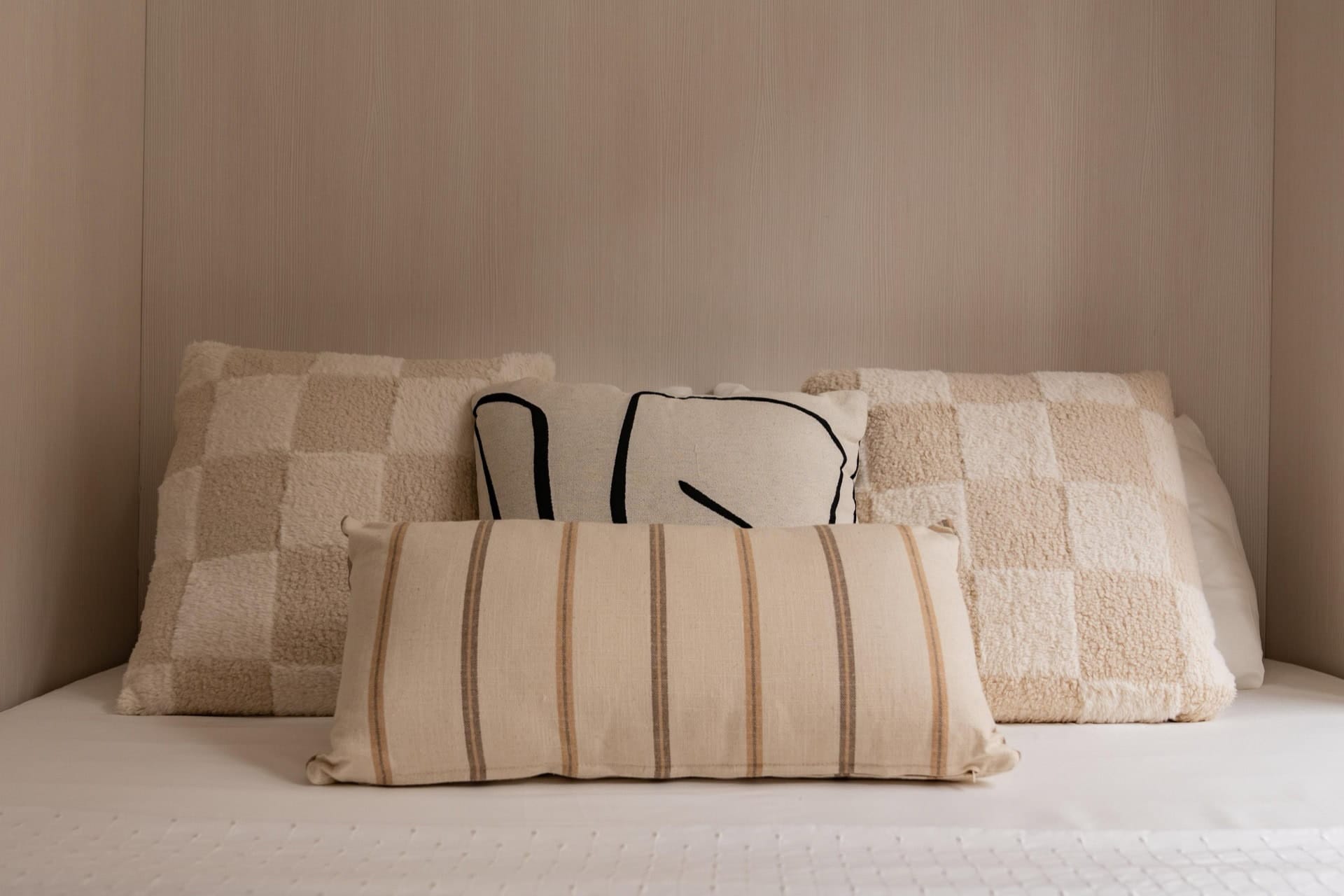 Stilvolles Schlafzimmer in einer Wohnung in Pržno, Montenegro: helle Wandgestaltung und Dekokissen auf dem Doppelbett.