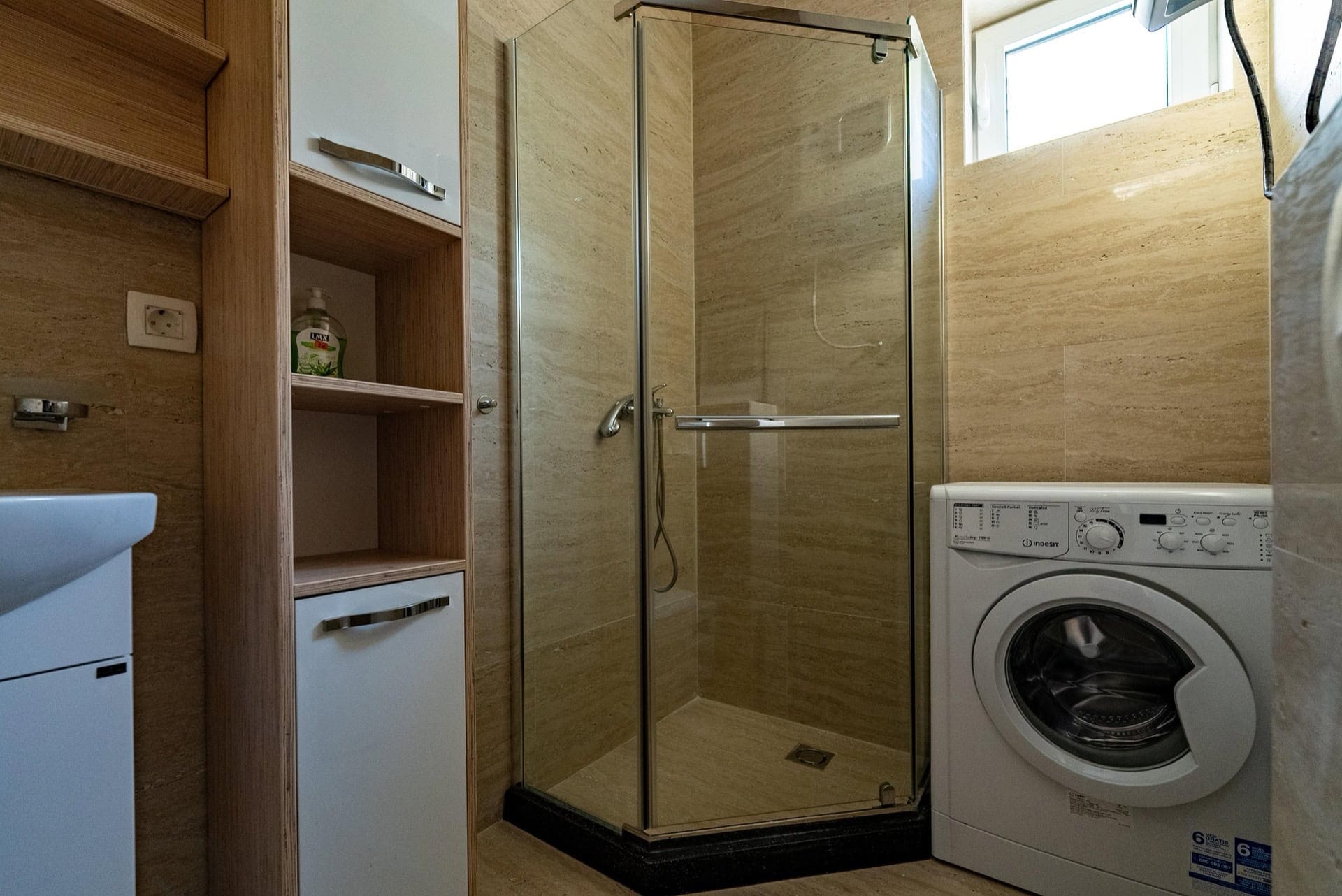 Modernes Badezimmer in einer Wohnung, Pržno, Montenegro: Duschkabine, Waschmaschine und Möbel aus hellem Holz.