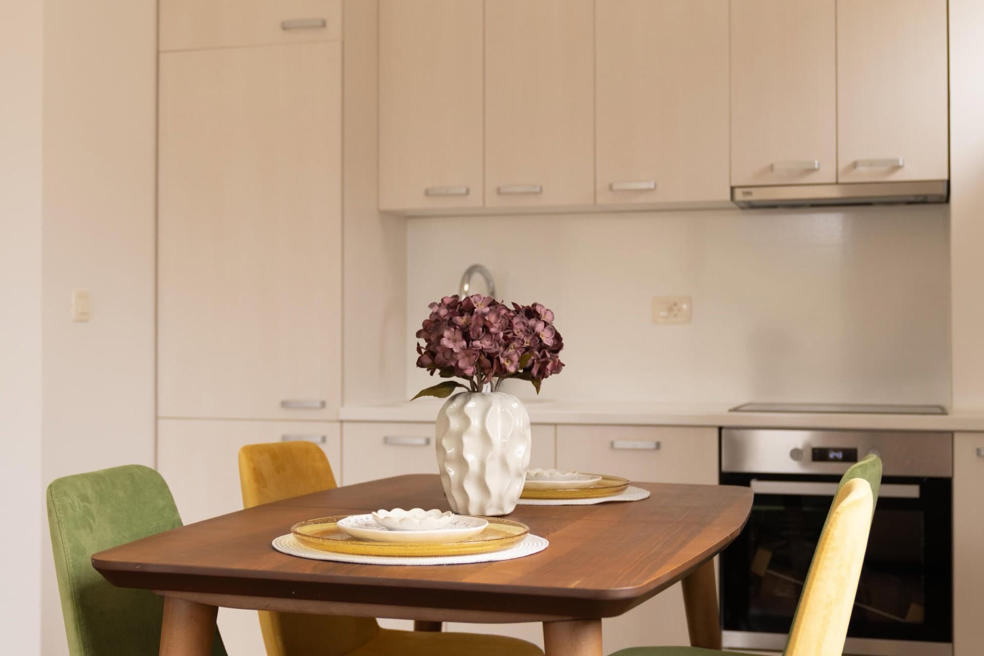 Moderne Küche in einer Wohnung in Pržno, Montenegro: Esstisch mit bunten Stühlen und helle Küchenzeile.