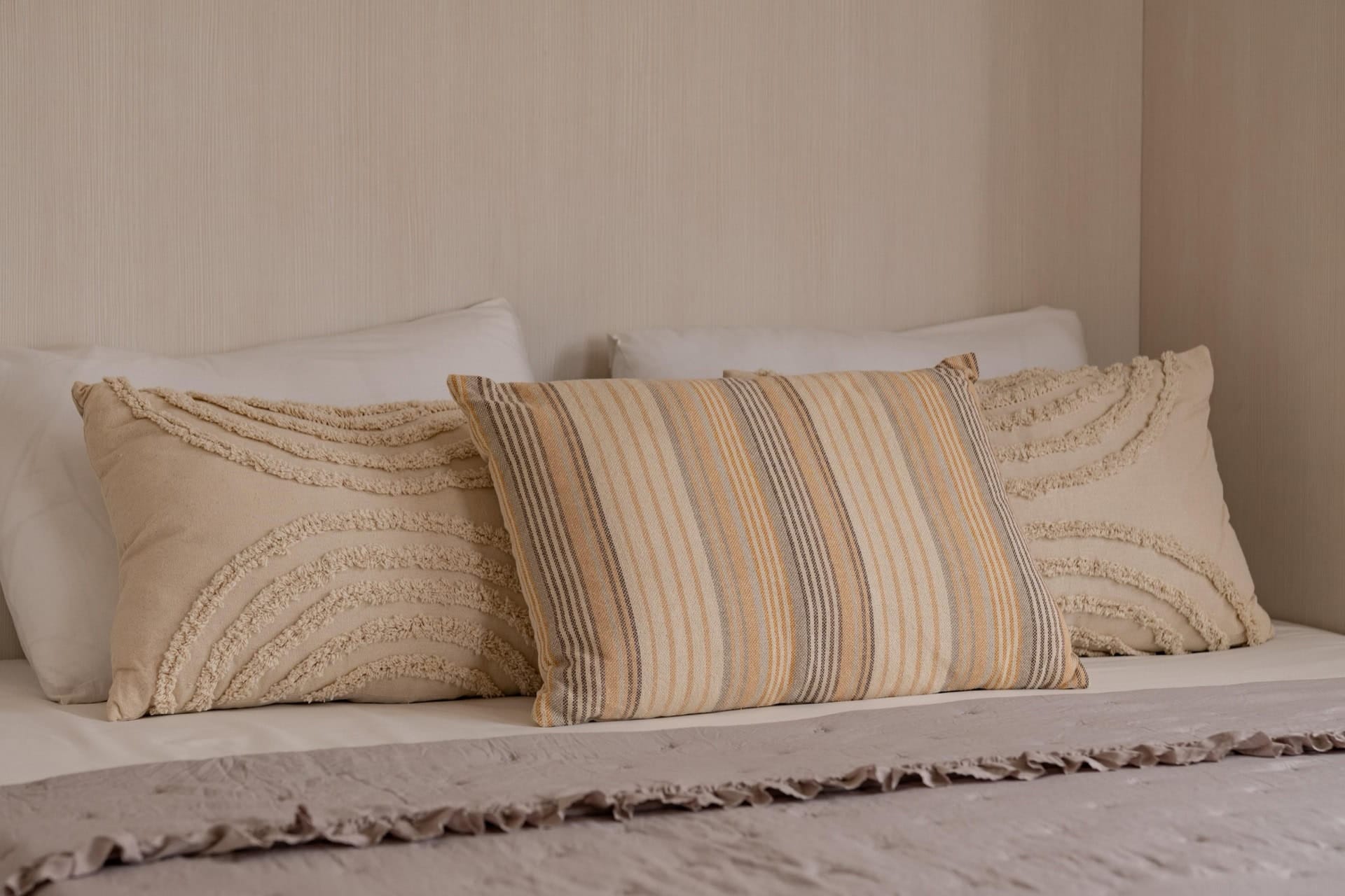 Gemütliches Schlafzimmer in einer Wohnung in Pržno, Montenegro: helle Dekokissen und stilvolle Bettwäsche auf dem Bett.