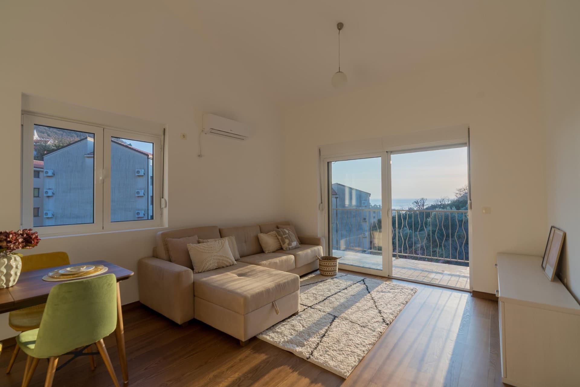 Helles Wohnzimmer mit beigem Sofa und Zugang zum Balkon mit Meerblick in einer Wohnung, Pržno, Montenegro.