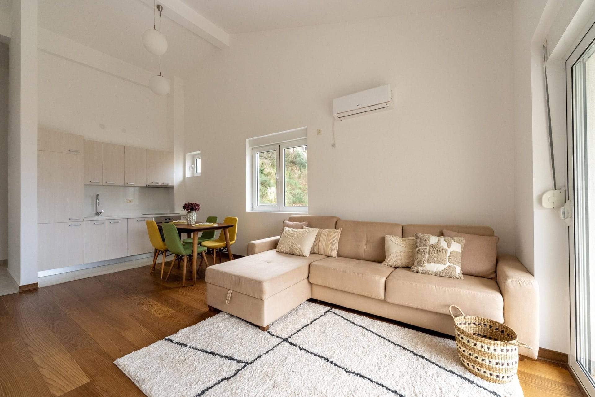 Helles Wohnzimmer mit Küche in einer Wohnung in Pržno, Montenegro: beiges Sofa, Essbereich und moderne Ausstattung.