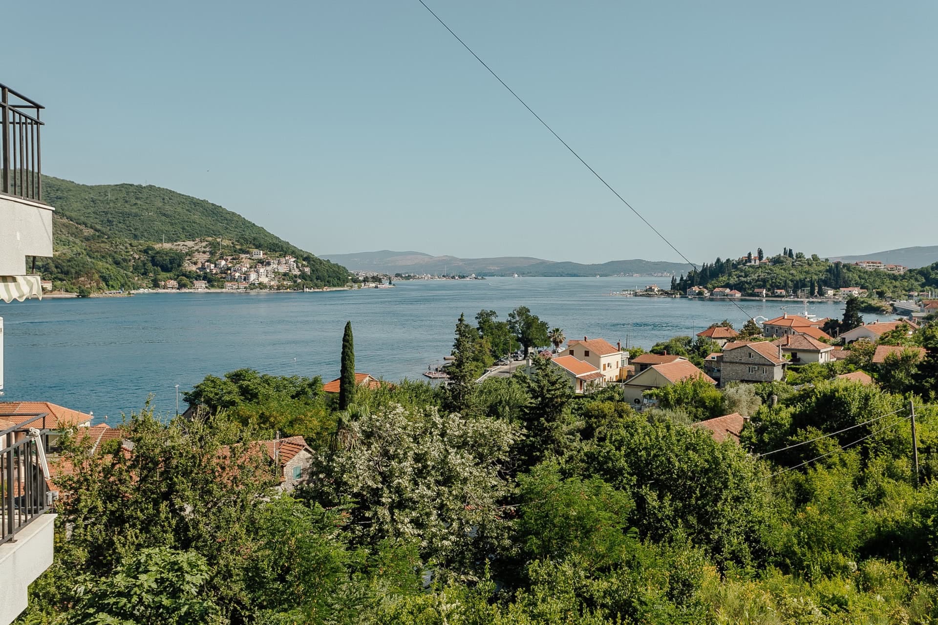 Panoramablick vom Balkon der Wohnung in Kamenari, Montenegro: Bucht von Kotor, Berge, Grün und Ziegeldächer der Häuser.