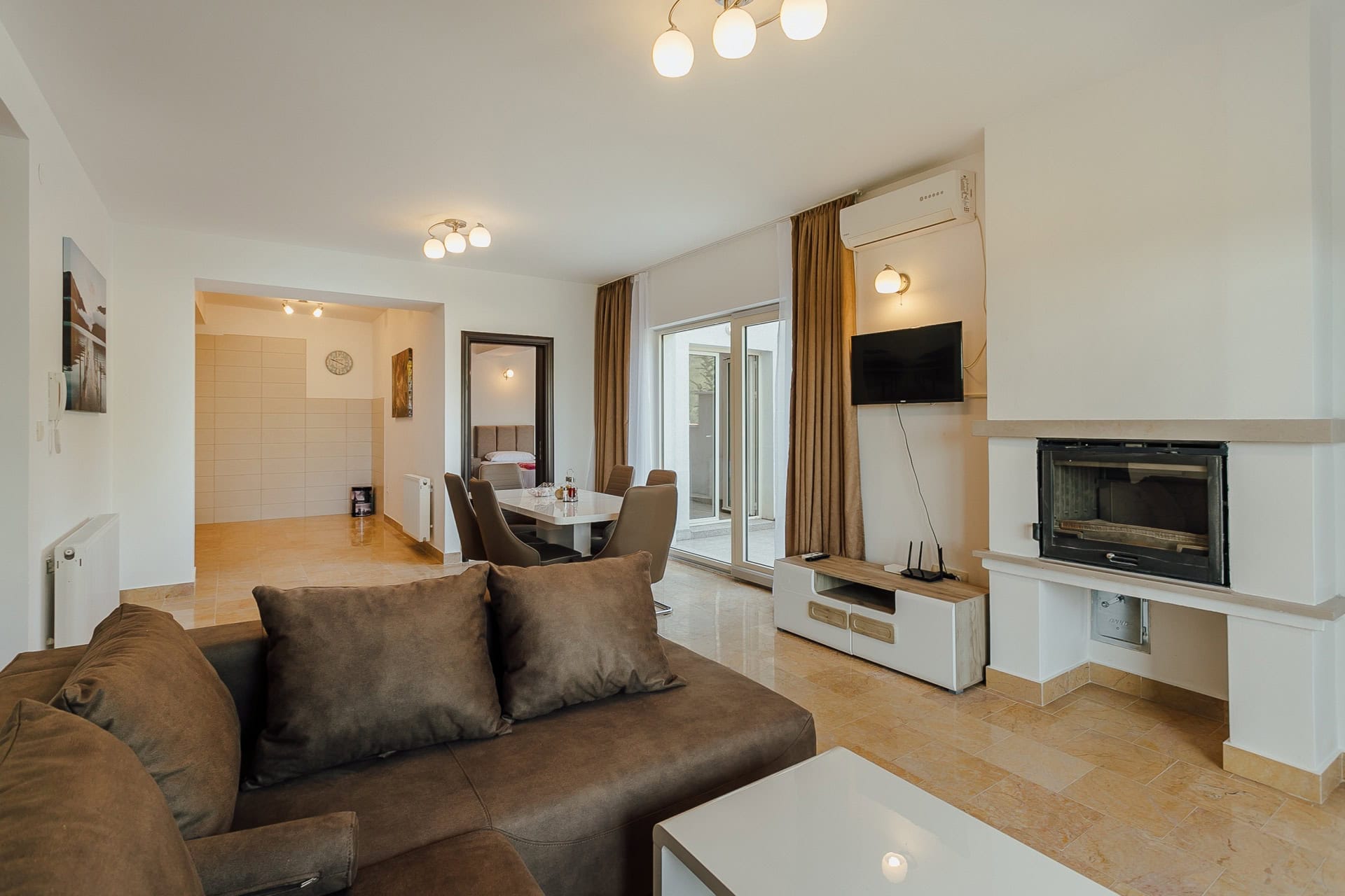 Wohnzimmer mit Kamin, Polstermöbeln und Essbereich in einer Wohnung in Kamenari, Montenegro.