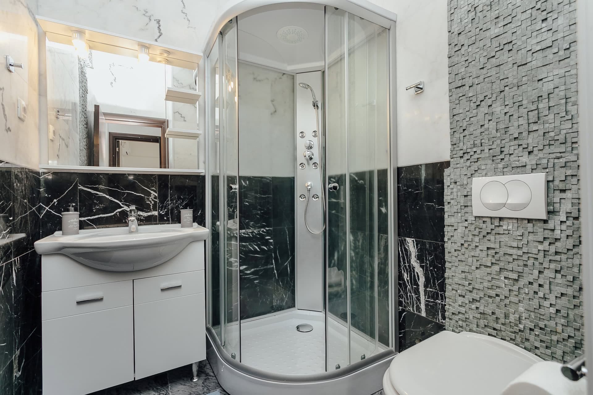 Modernes Badezimmer mit Duschkabine und schwarzer Marmorverkleidung in einer Wohnung, Kamenari, Montenegro.