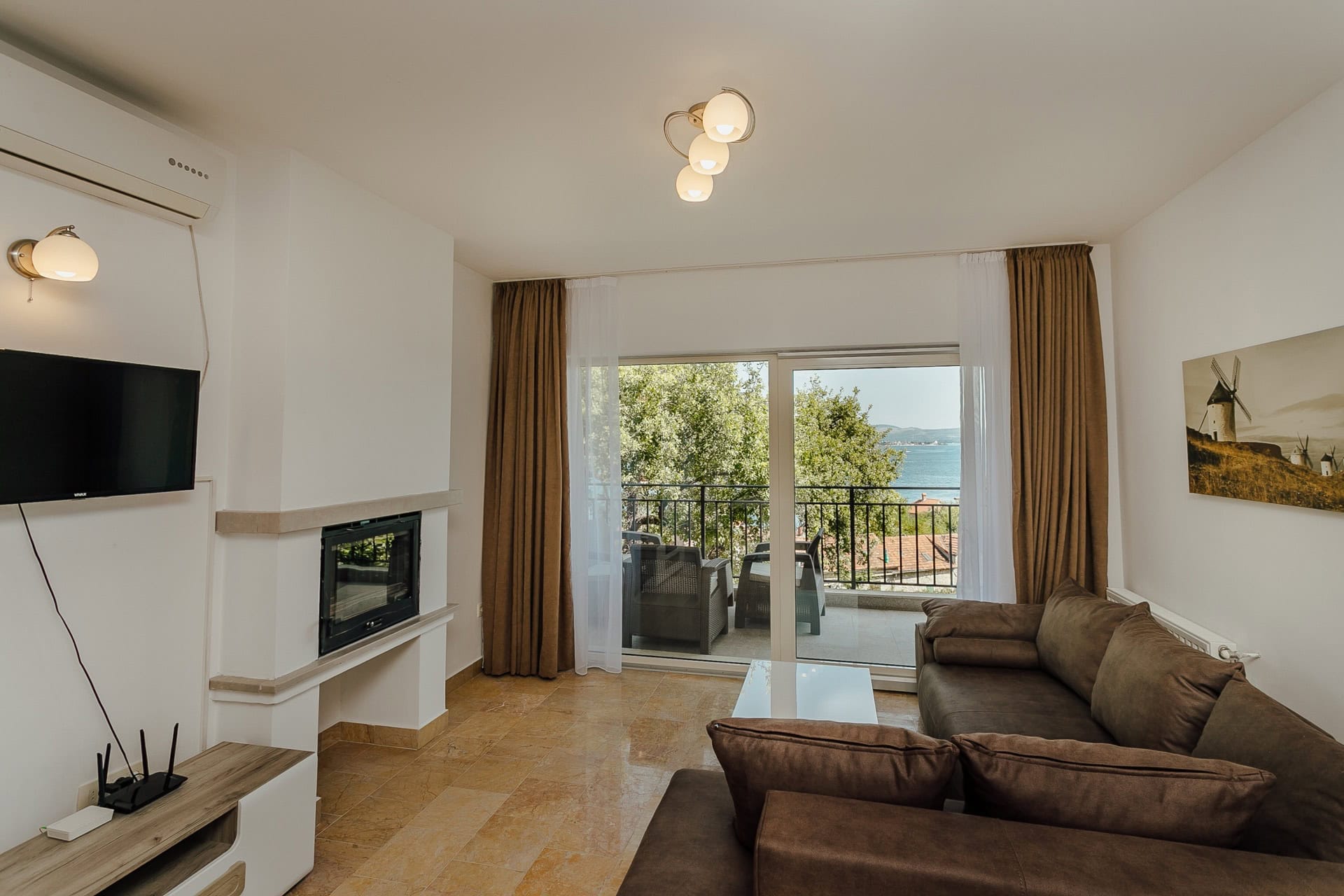 Wohnzimmer mit Kamin und Zugang zur Terrasse mit Meerblick in einer Wohnung in Kamenari, Montenegro.