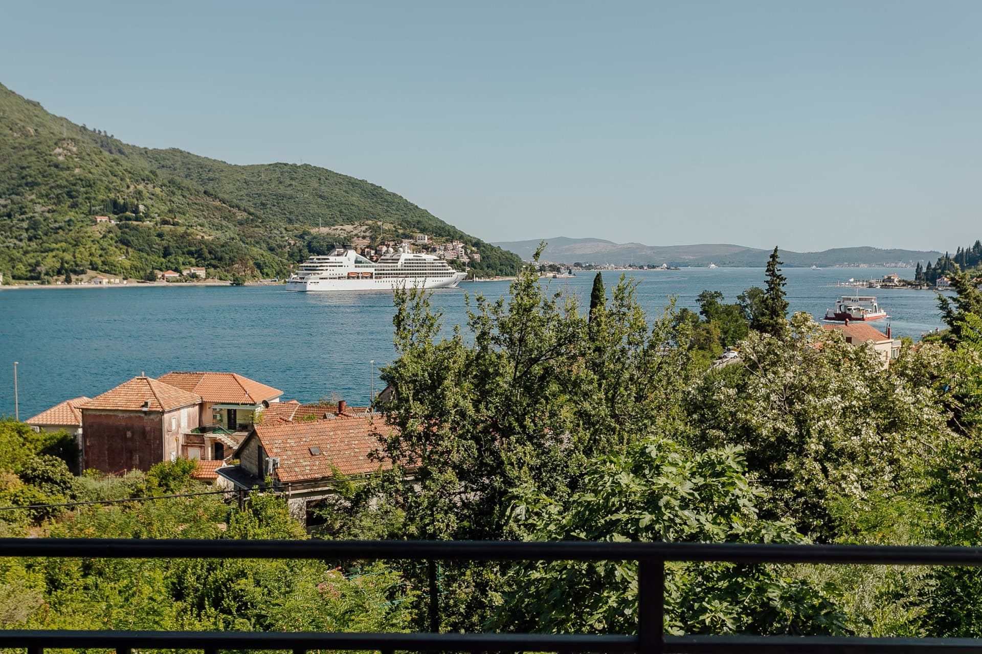 Blick vom Balkon der Wohnung in Kamenari, Montenegro: Panorama der Bucht von Kotor, Berge und ein Kreuzfahrtschiff.