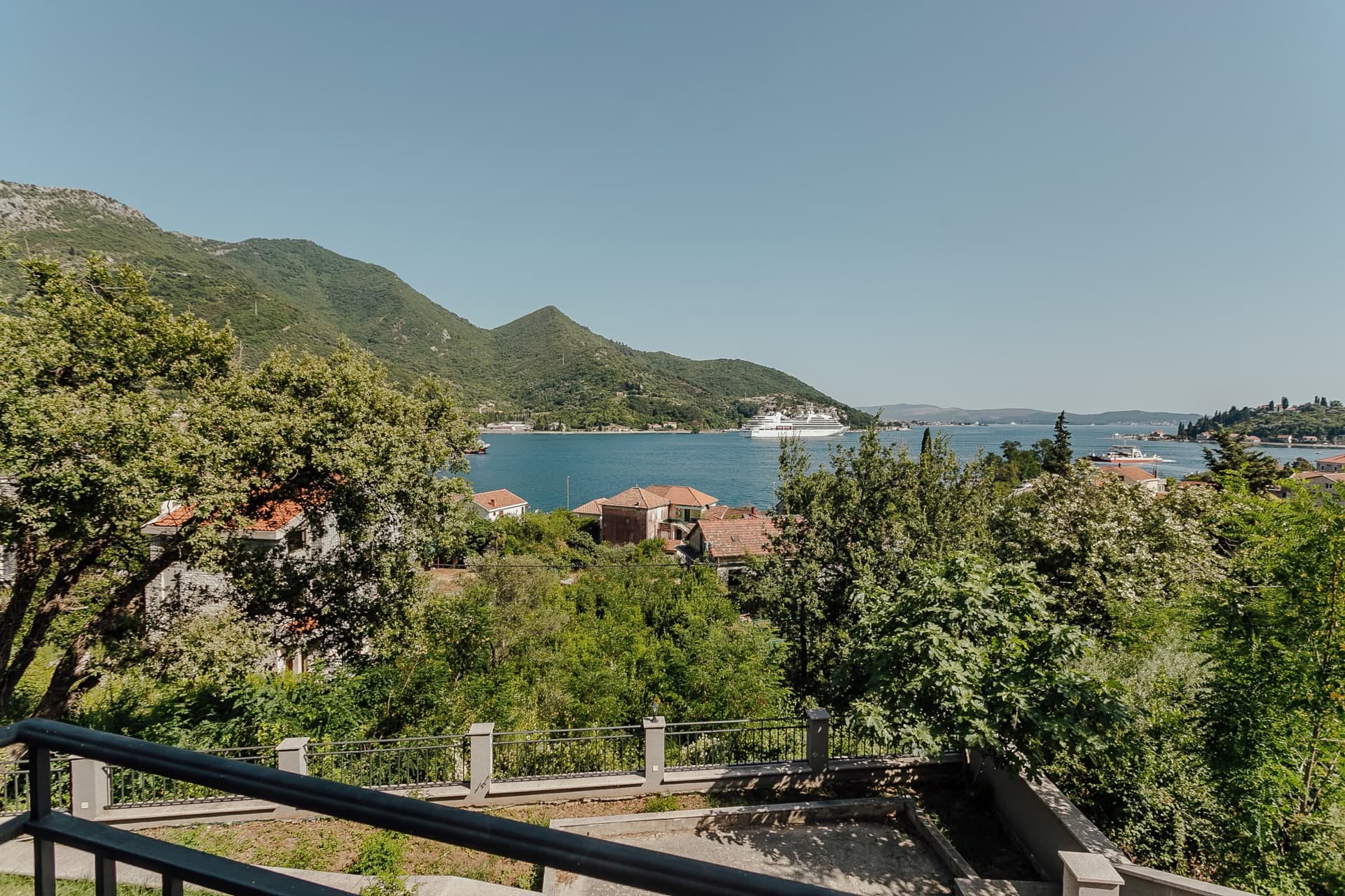 Blick vom Balkon der Wohnung in Kamenari, Montenegro: Panorama der Bucht von Kotor, Berge und ein Kreuzfahrtschiff.