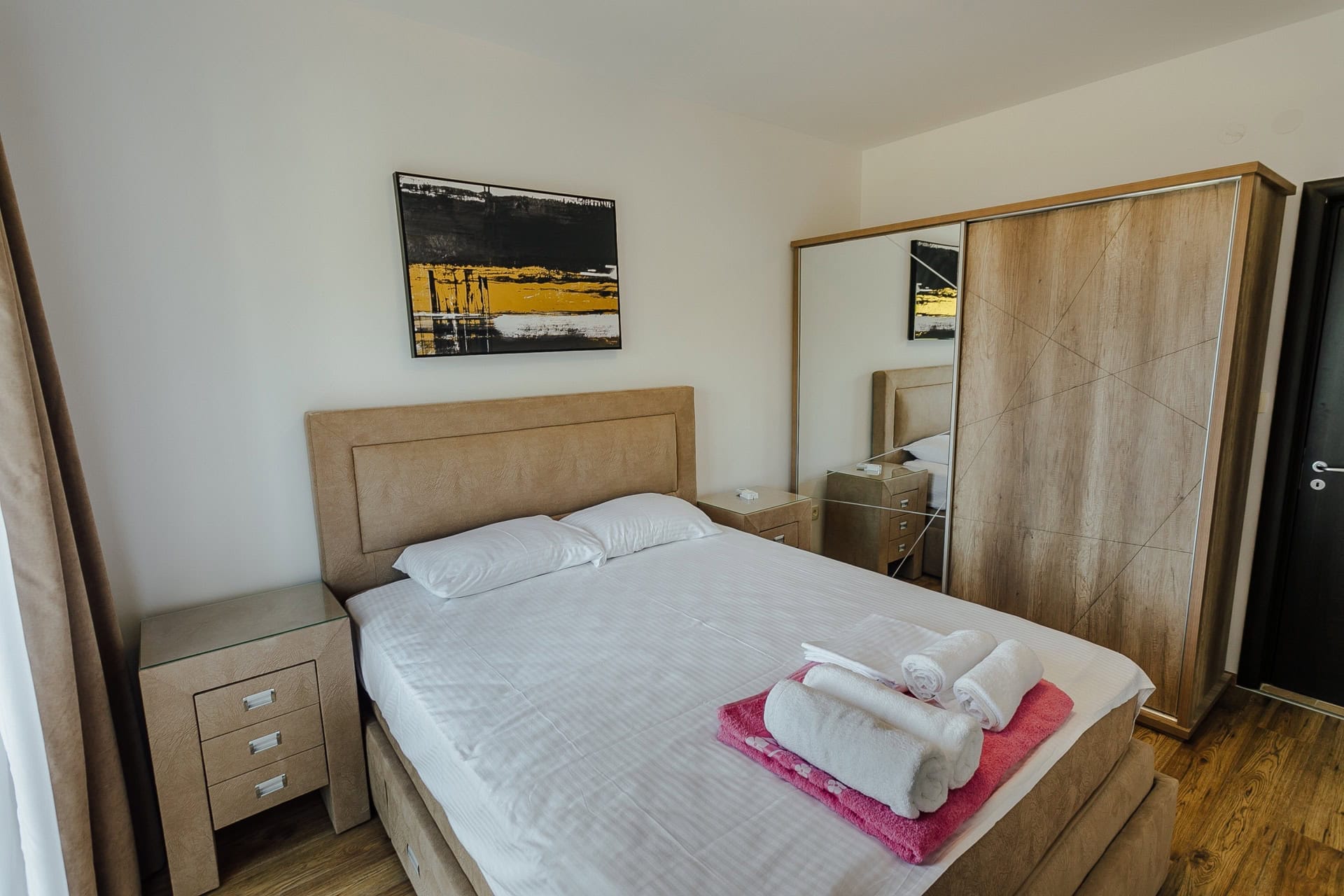 Schlafzimmer in einer Wohnung in Kamenari, Montenegro: Doppelbett, Kleiderschrank mit Spiegel und Nachttische im Interieur.
