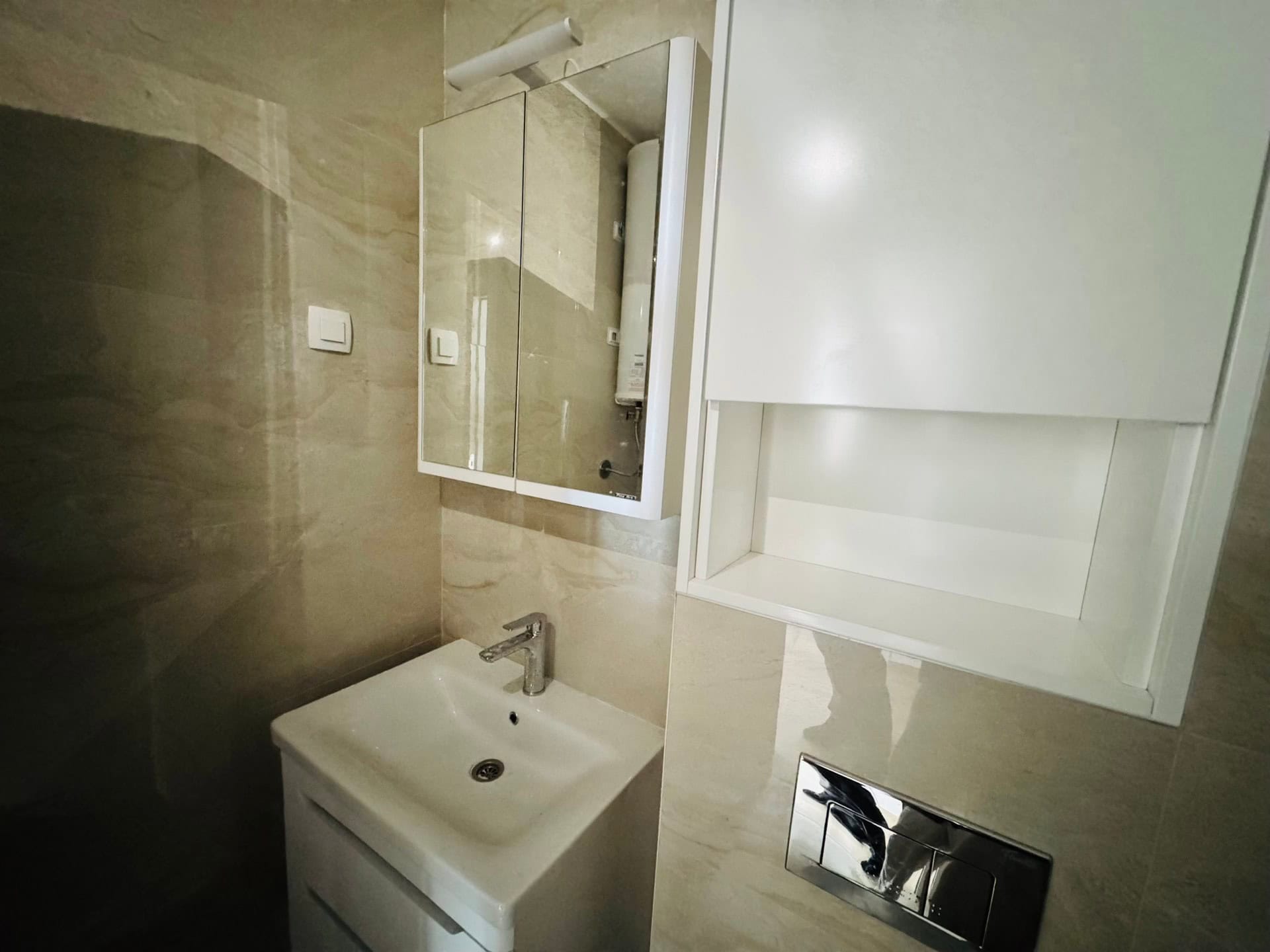 Beyaz mobilyalı ve bej fayanslı modern banyo, Bečići, Karadağ.