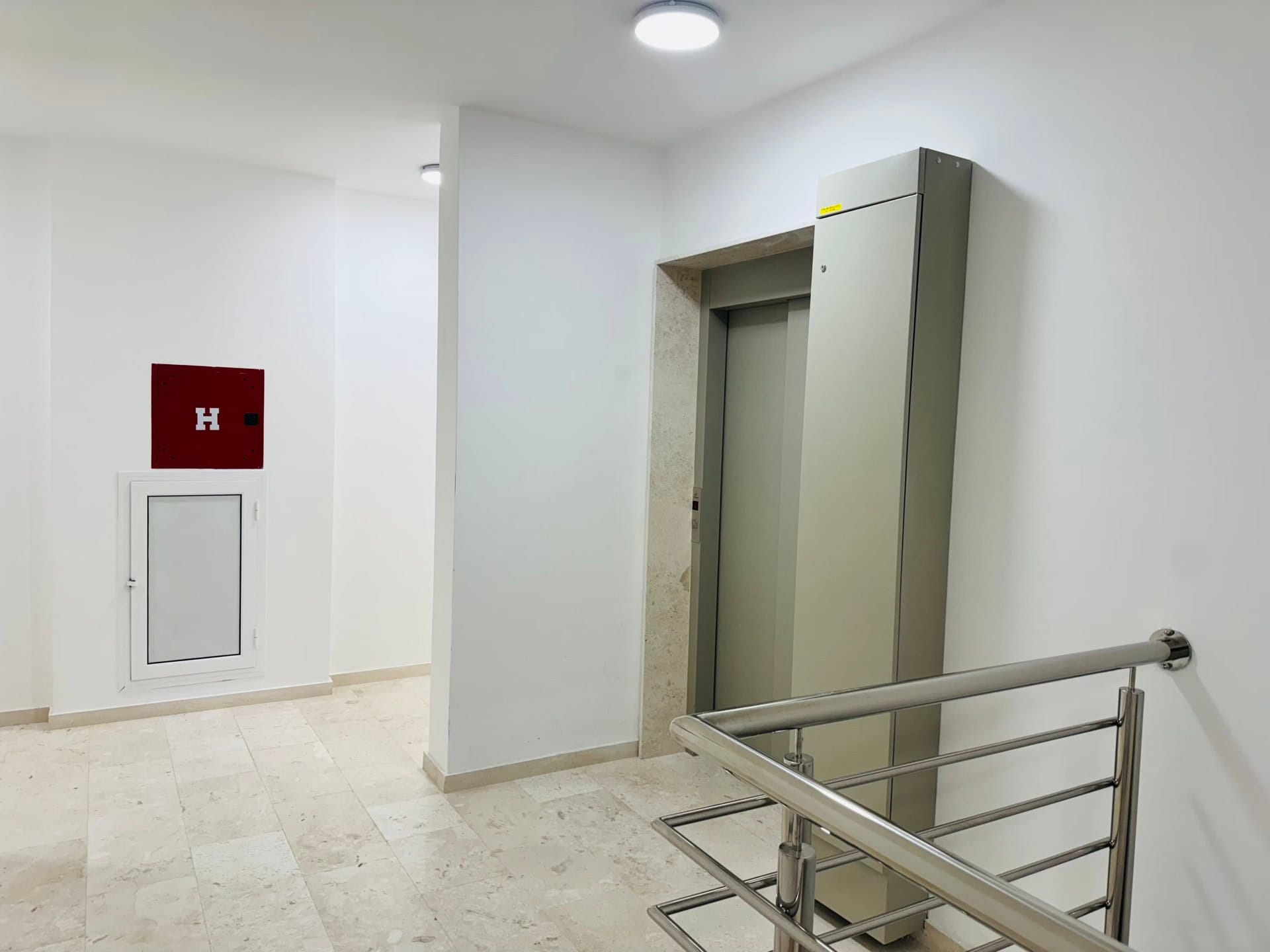 Karadağ, Bečići’deki konut kompleksinde modern asansör holü: aydınlık kaplama, fayans ve metal korkuluklar.