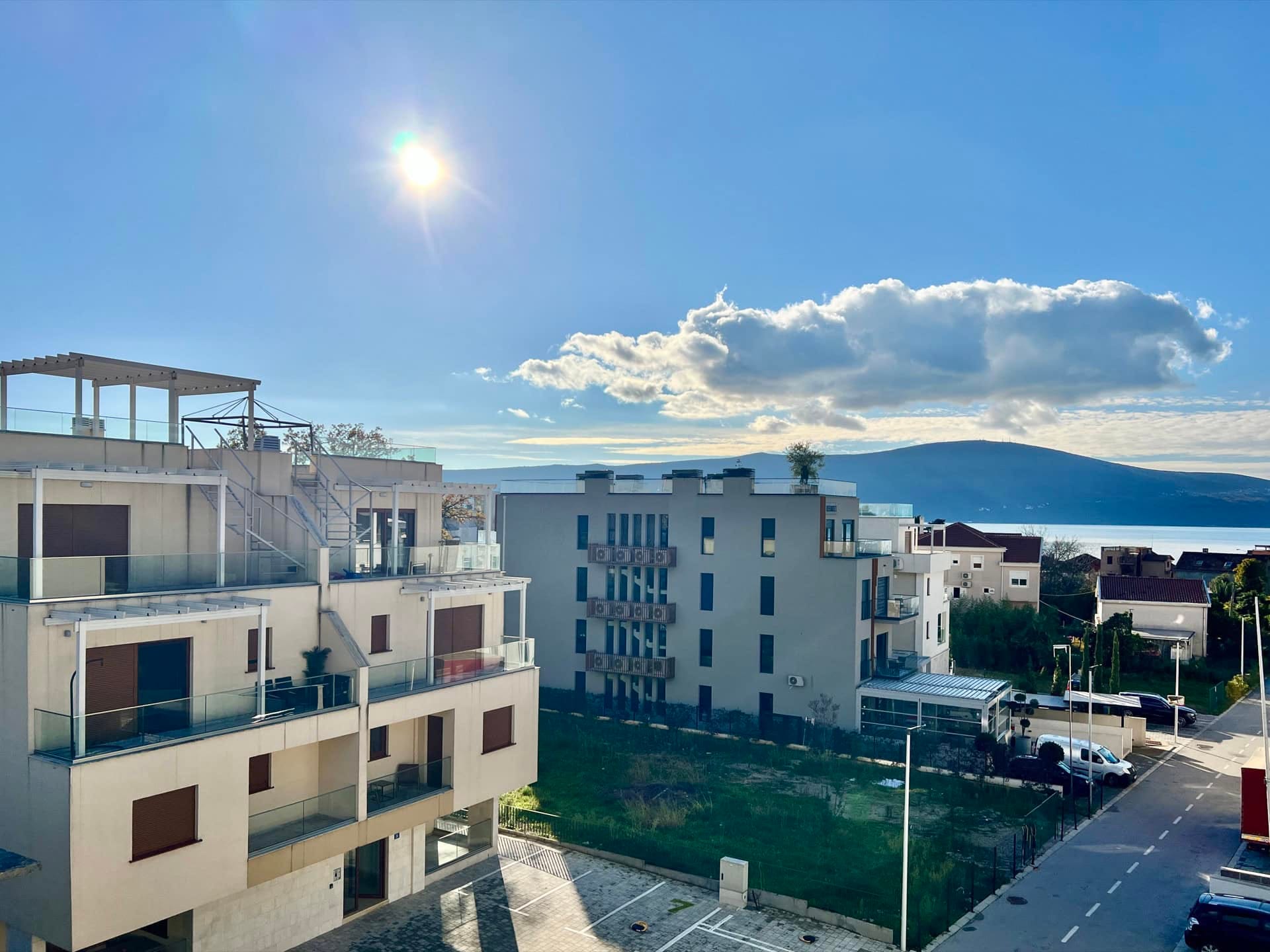 Pogled na moderne stambene komplekse u Tivtu, Crna Gora, sa terasama i panoramskim pogledom na planine i more.