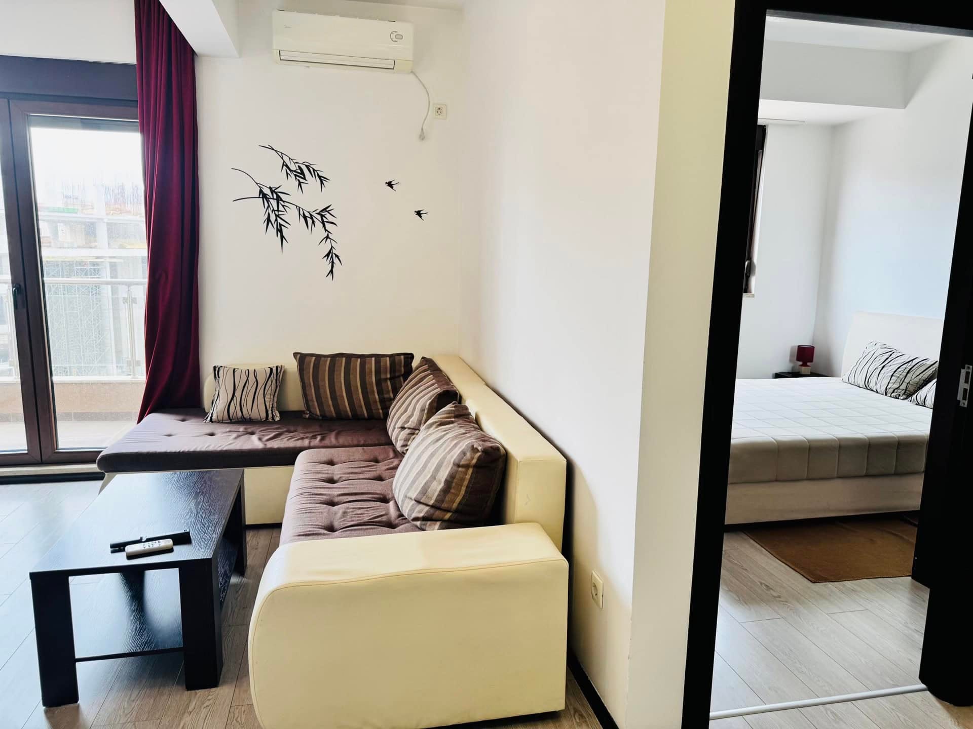 Living room with a corner sofa and bedroom in an apartment in Budva, Montenegro: modern interior with access to the balcony.