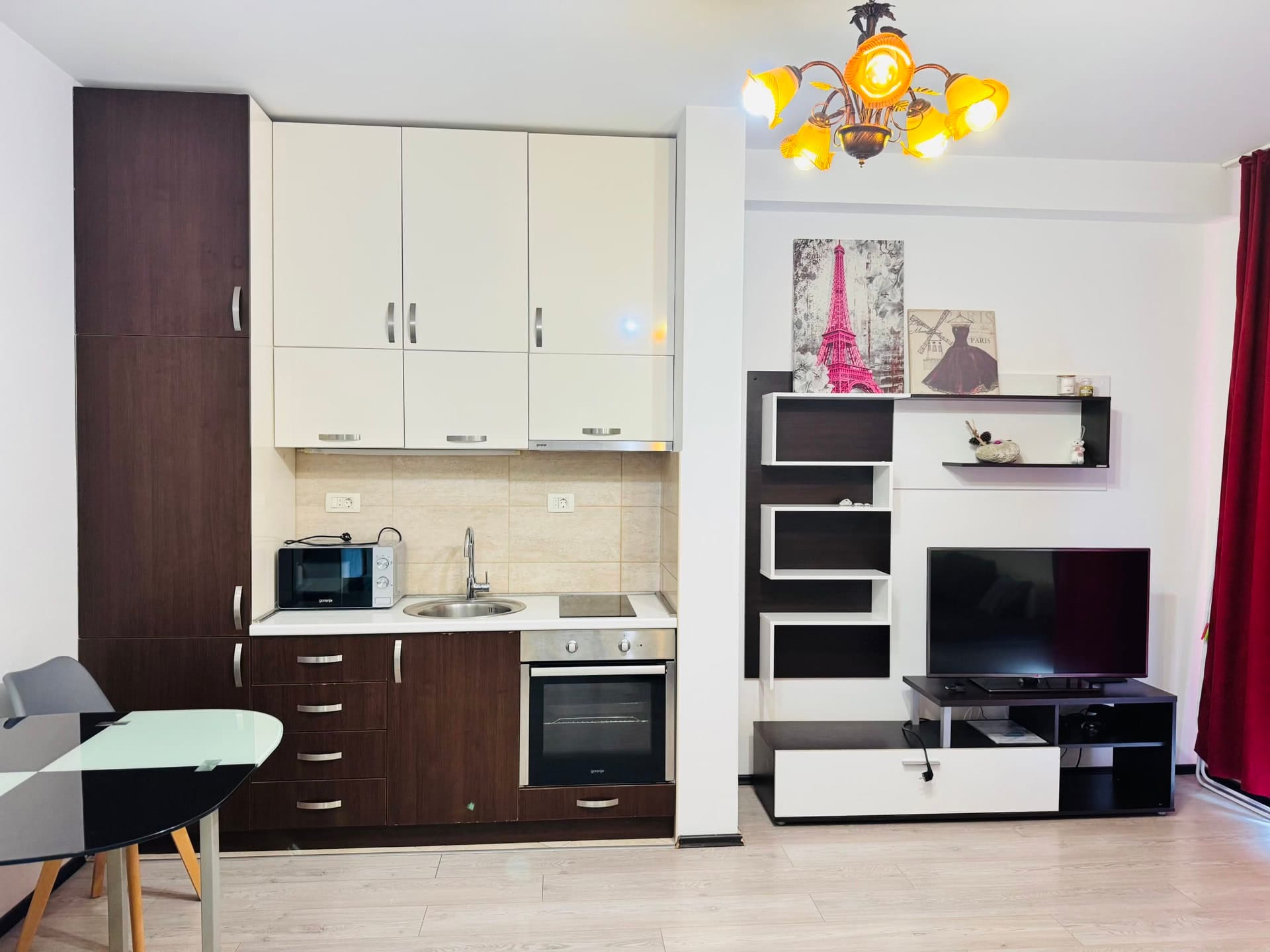 Modern kitchen-living room in an apartment in Budva, Montenegro: kitchen set, built-in appliances, and TV area.