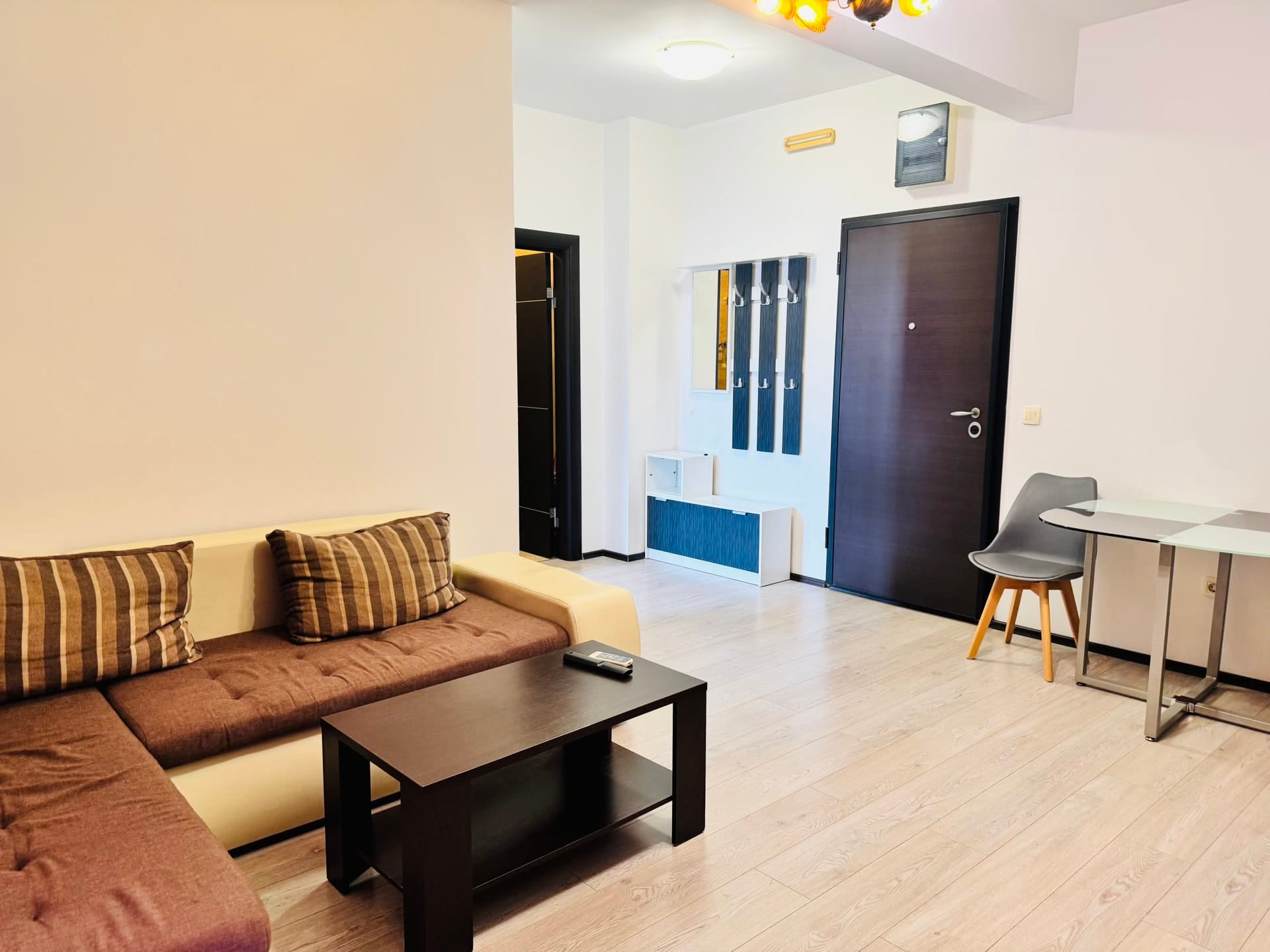 Living room in an apartment in Budva, Montenegro: brown sofa, coffee table, dining area, and light laminate flooring.