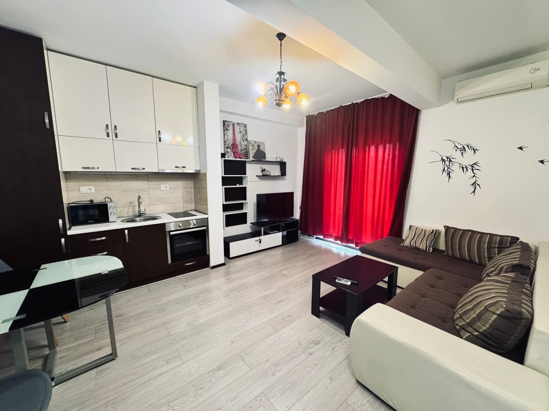Modern living room with kitchen in an apartment in Budva, Montenegro: corner sofa, dining area, and bright interior.