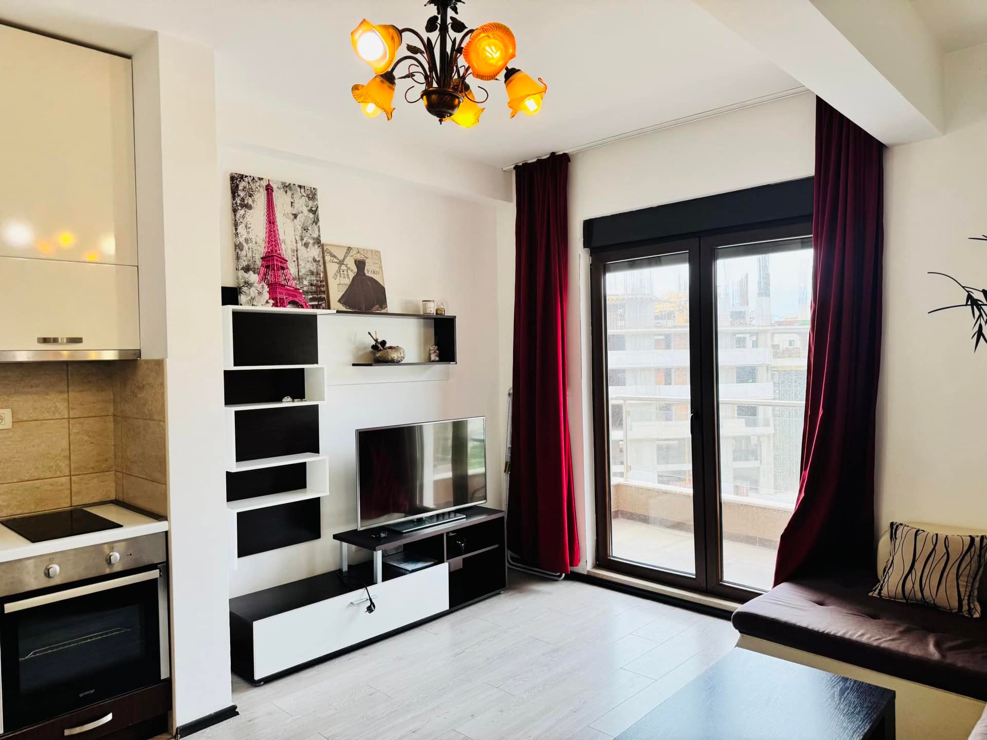 Living room with kitchen in an apartment in Budva, Montenegro: modern furniture, TV area, access to the balcony, and panoramic windows.