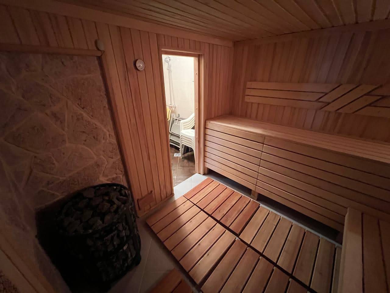 Holzsauna mit Steinverkleidung in einer Villa in Kamenari, Montenegro: Innenraum der Sauna mit Bänken und Ofen.