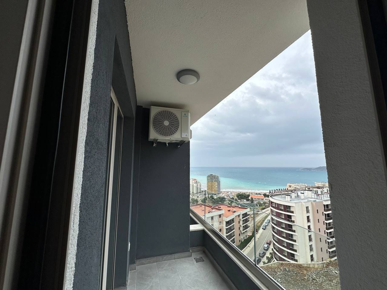 Balkon moderne stana u Bečićima, Crna Gora, sa panoramskim pogledom na more i grad, staklena ograda.