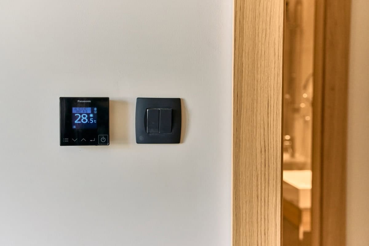 Termostat Panasonic i prekidač za svetlo u modernom stanu u Tivtu, Crna Gora, sa završnom obradom u imitaciji drveta.
