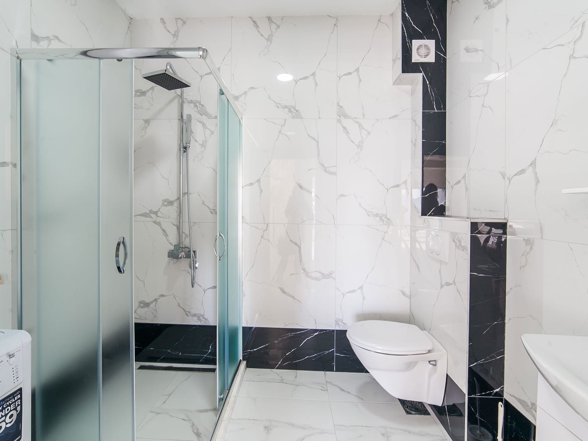 Modern bathroom in an apartment in Bečići, Montenegro: shower cabin, marble-look tile finish, and plumbing fixtures.